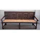 A 17th century and later oak settle with carved frieze panel back on turned supports,