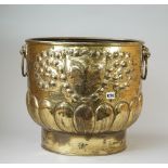 A Dutch gilt brass log bin embossed with a Fleur de lys shield flanked by twin lion ring handles,