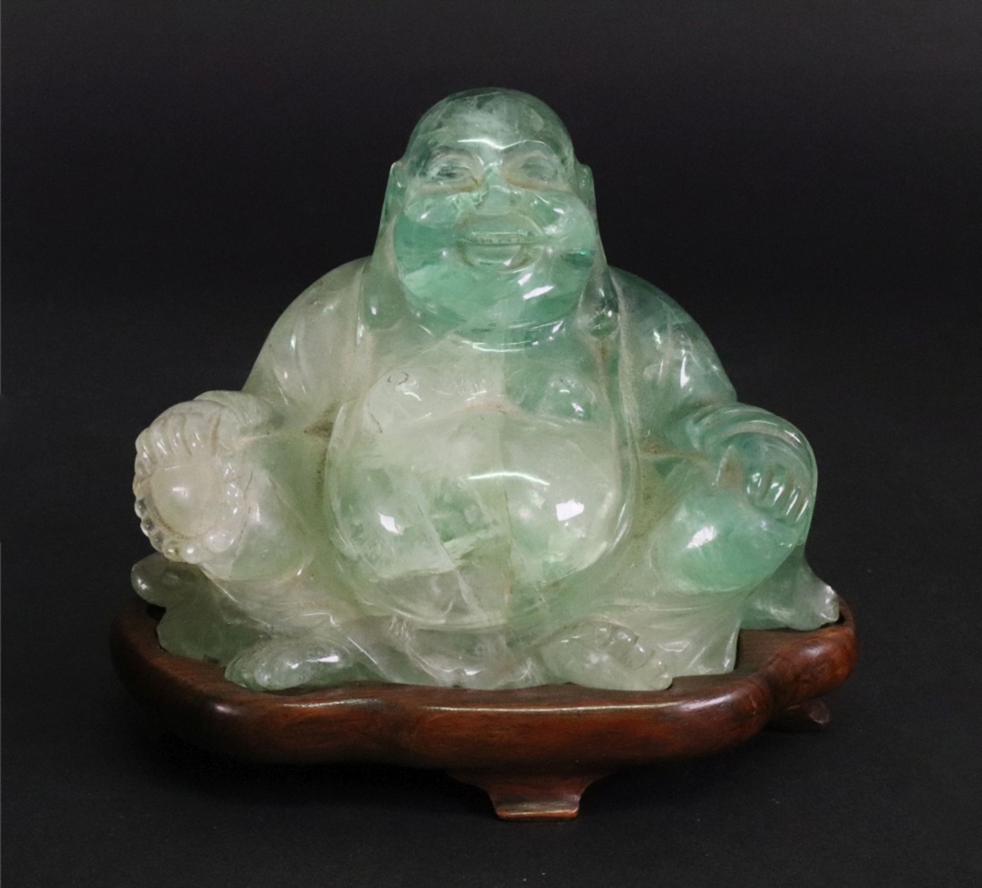 A Chinese carved green quartz figure of a seated Buddha, 20th century, on a carved rosewood stand,