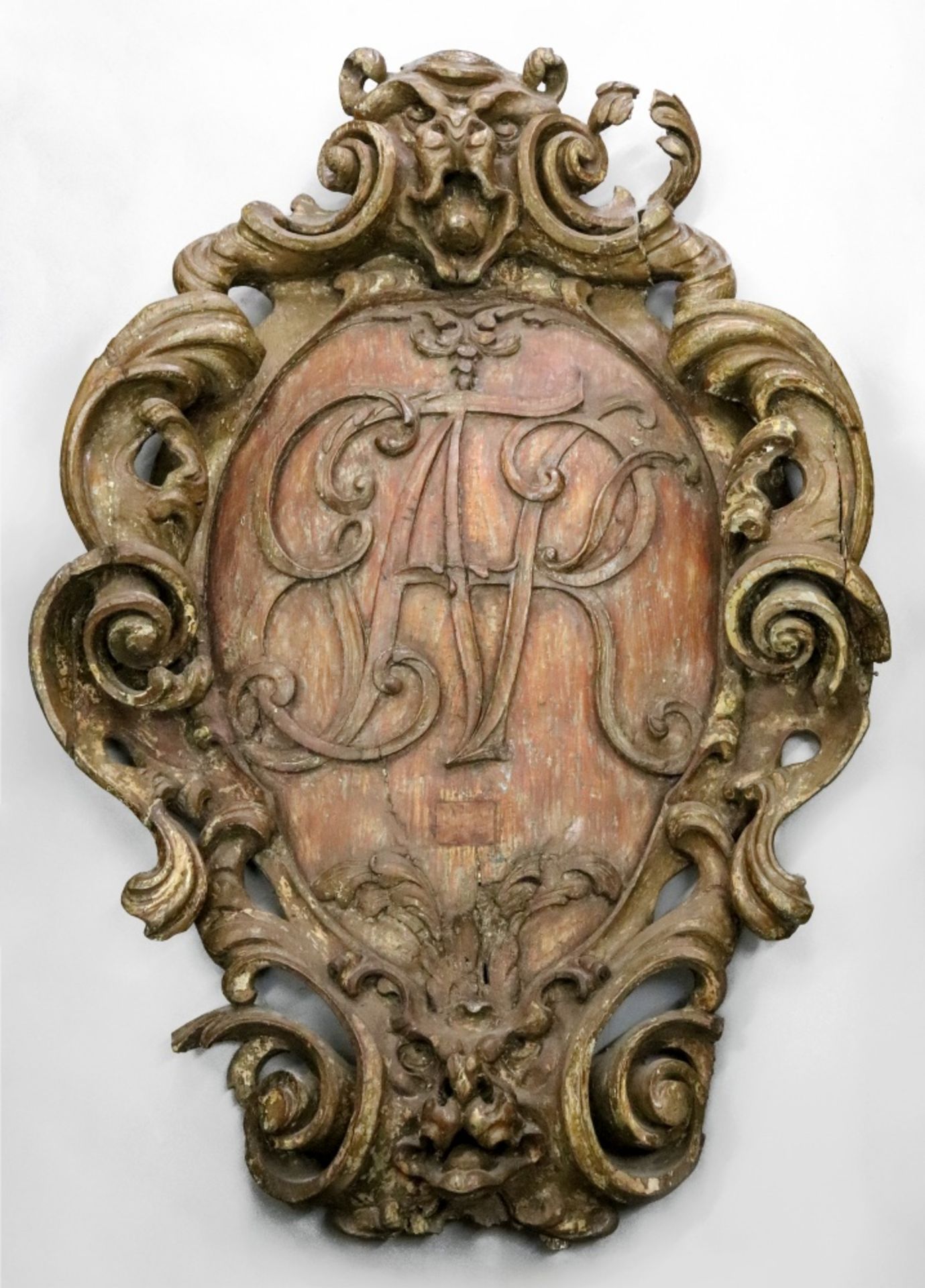 A large and impressive early 18th century pine wall shield, of cartouche shape, polychrome painted,