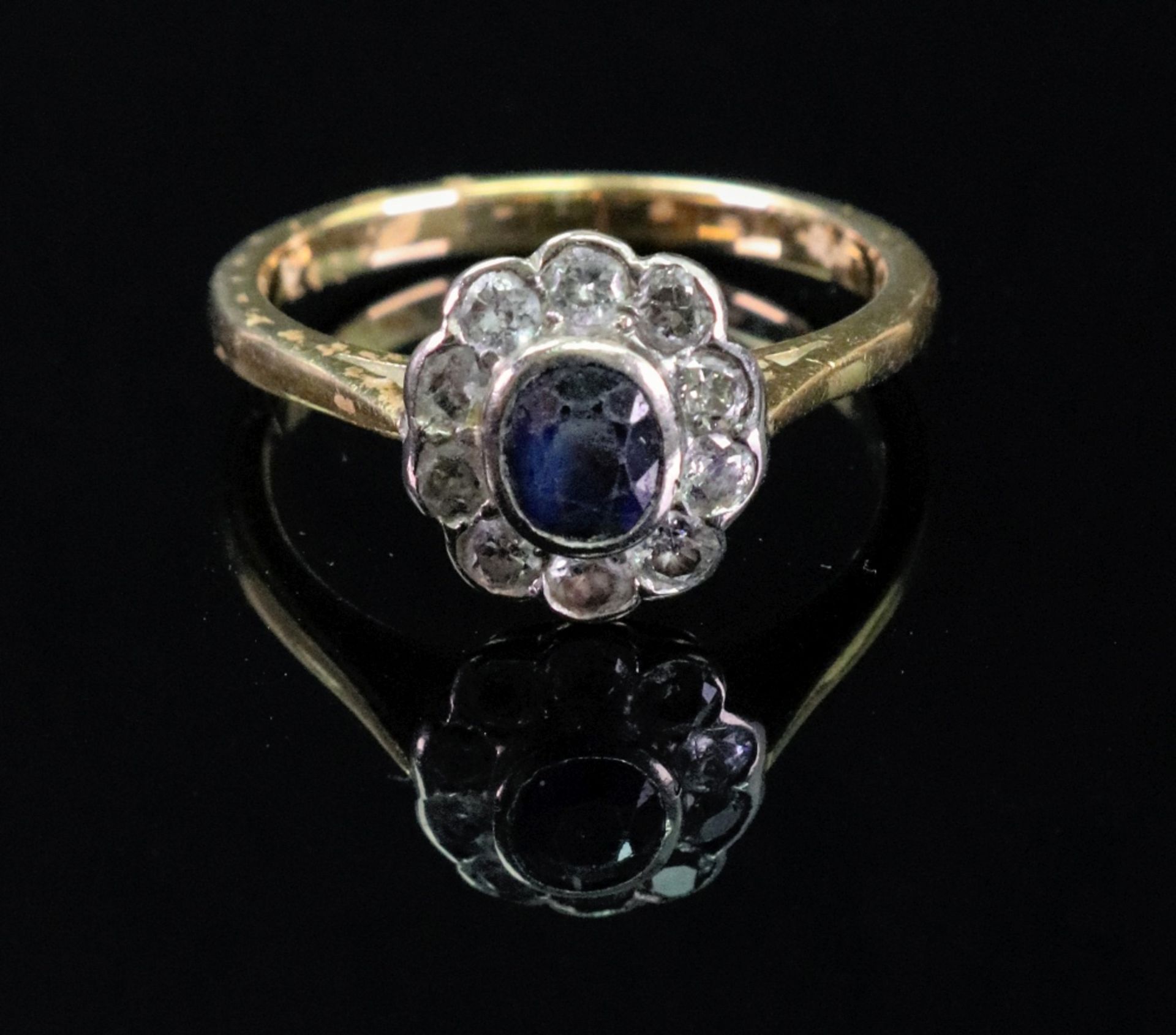 A sapphire and diamond cluster ring, the collet-set oval-cut sapphire,