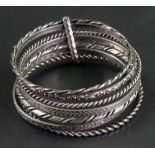 A semainier bangle, composed of a collection of seven silver bangles of varying designs,