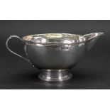 An Arts & Crafts silver milk jug, Birmingham 1920, makers mark T B, circular, spot hammered,