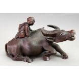 A Chinese carved hardwood figure of a child riding on the back of a water buffalo,