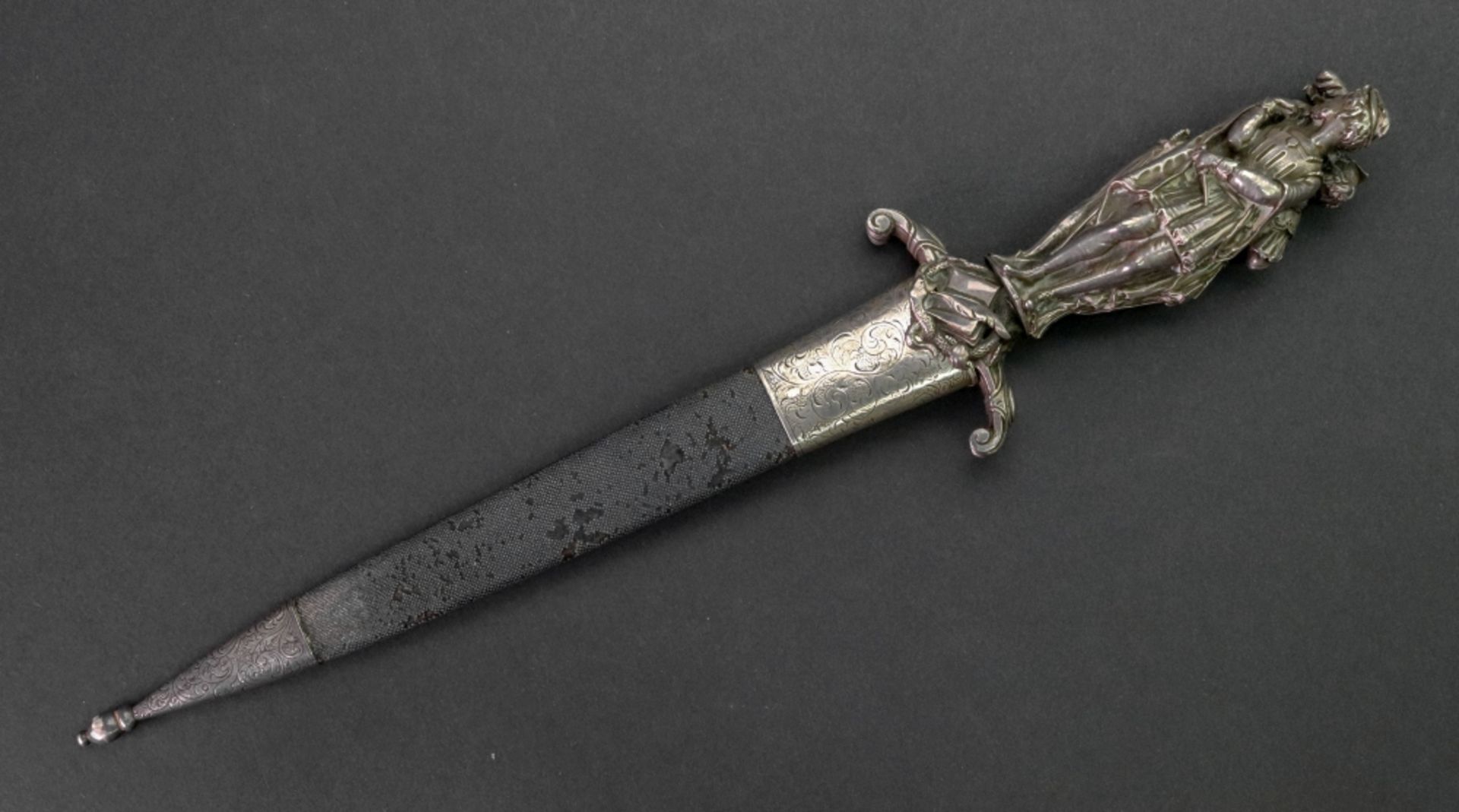 A silver handled dagger, cast as three standing figures dressed in period costume,