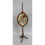 A Victorian mahogany pole screen, circa 1870, with foliate decoration and stringing,