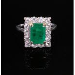 An emerald and diamond ring, the central rectangular step-cut emerald, approximately 2.