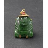 A gold mounted carved nephrite pendant, designed as a seated Buddha wearing a red paste-set hat,
