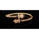 A sapphire and diamond-set yellow precious metal hinged bangle of rope-twist cross over torc design,