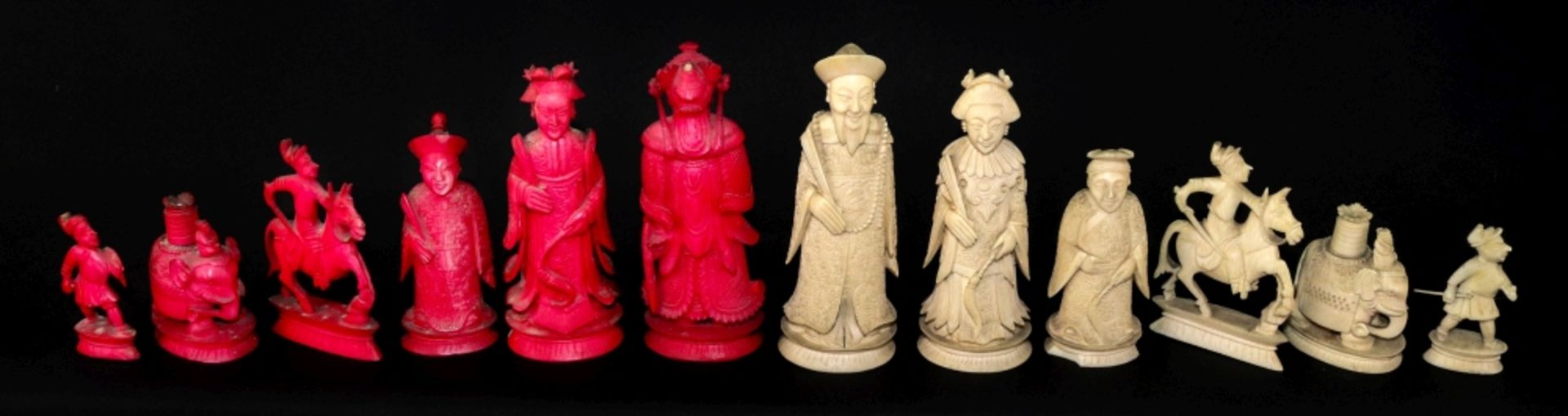 A Chinese carved ivory chess set, 19th century, one half stained red, the other natural, Kings 10.