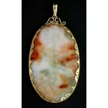 A gold mounted varicoloured jade large oval pendant, fitted with a scroll pierced suspension, 25.