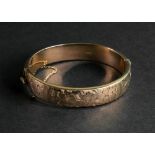 A 9ct gold hollow hinged bangle, of oval design, engraved with a repeat flowerhead motif,