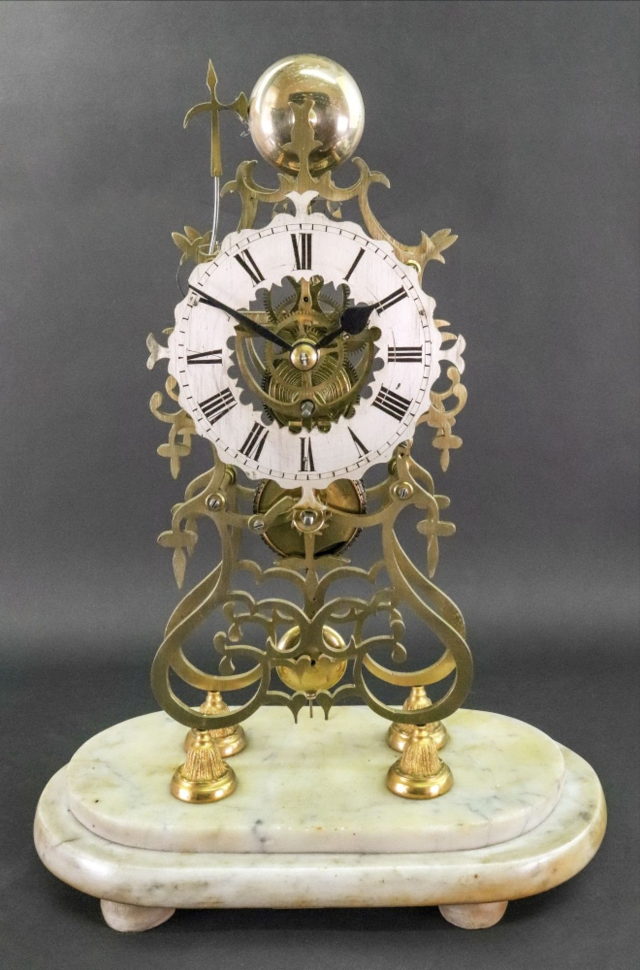 A Victorian brass skeleton clock, of open scrollwork form, the silvered dial with Roman numerals,