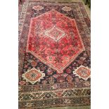 A South Persian rug, with a central lozenge surrounded by a repeated design on a red ground,