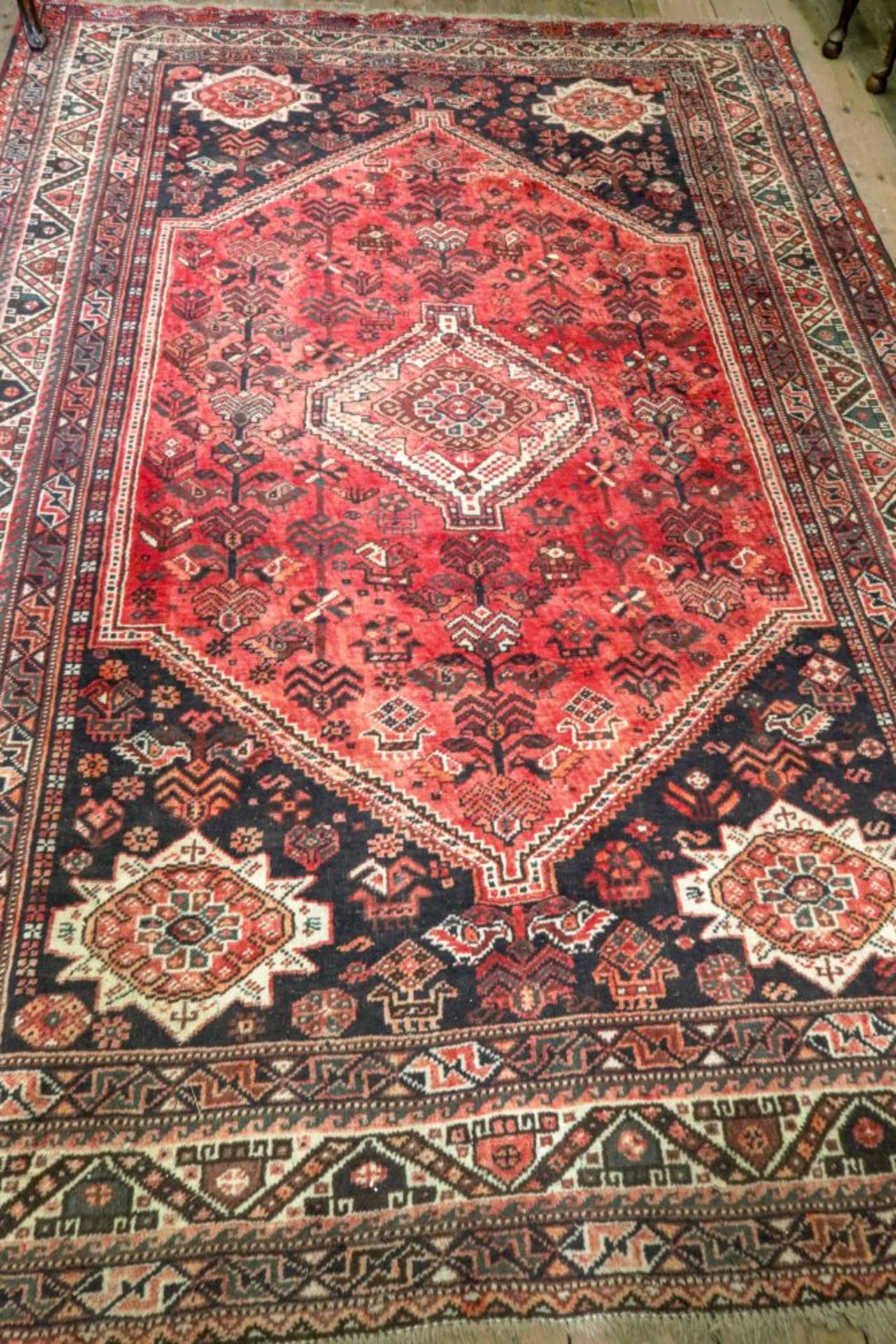 A South Persian rug, with a central lozenge surrounded by a repeated design on a red ground,