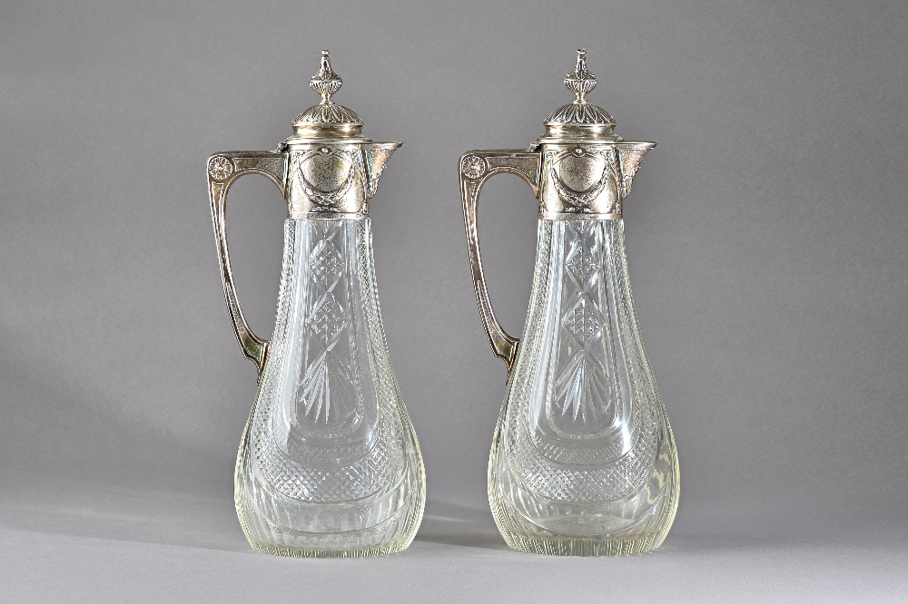 A copy of a pair of Faberge faceted glass claret jugs, each body of swept oval form,