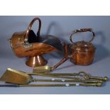 A 19th century copper helmet shaped coal scuttle, a large kettle and a set of brass fire tools, (5).