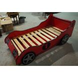 A 20th century single bed formed as a red race car with pull out bed beneath,