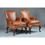 A pair of George III style studded brown leather upholstered armchairs with serpentine seats on