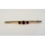 A silver and gold backed ruby set three stone bar brooch,