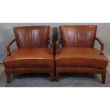 A pair of 20th century mahogany framed low open armchairs with tan leather upholstery on tapering