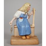 A Russian biscuit porcelain figure of an old woman carding wool, Gardner factory, late 19th century,