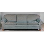 A large modern blue upholstered sofa with roll over arms on tapering block supports,