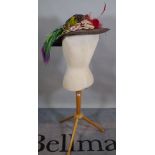 A 20th century tailor's dummy on beech tripod base, together with a colourful ladies hat.