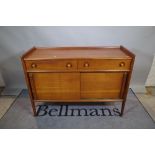 Kendxa; a mid 20th century hardwood sideboard with two drawers over sliding cupboard base,