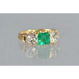 A gold, emerald and diamond set three stone ring,