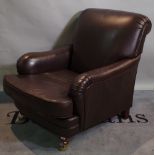 Marks & Spencer; a 20th century low armchair with brown leather upholstery on tapering supports.