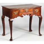 A mid-18th century oak lowboy with three drawers about the shaped frieze resting on pad feet,