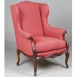 A Louis XV style wingback armchair on shell carved mahogany scroll supports, 72cm wide x 106cm high.