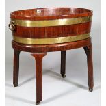 An 18th century brass cooper banded oval wine cooler with loop handles on canted square supports,