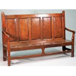 An 18th century oak settle with five panel back and open arms on canted block supports,