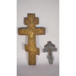 Two brass Russian icons, each relief cast crucifix form, the smaller with traces of blue enamel,