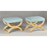 A pair of Empire style stools each with overstuffed rectangular tops on parcel gilt blue painted