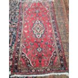 A Hamadan rug, Persian, the madder field with an oranage medallion, spandrels,