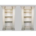 A pair of distressed white painted floor standing breakfront open bookcases, each on plinth base,