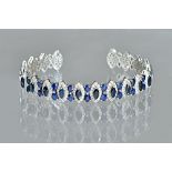 A white precious metal, sapphire and diamond set torc bangle,