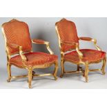 A pair of Louis XV style gilt framed open armchairs with serpentine seats on scroll supports,