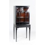 An ebonised display cabinet, with glazed door over pair of drawers on tapering square supports,
