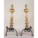 A pair of Georgian brass fire dogs with pineapple finials and turned body on a wrought iron base,