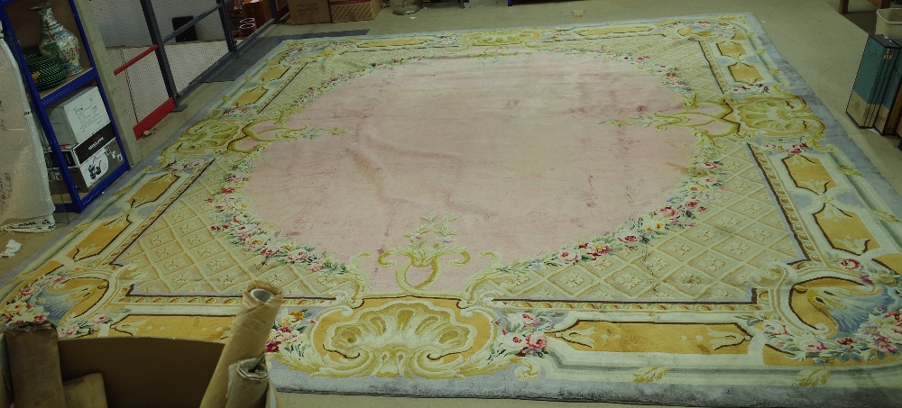 A Savonnerie carpet, French, the plain pale pink field with trellis spandrels and floral garlands,