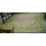 A Savonnerie carpet, French, the plain pale pink field with trellis spandrels and floral garlands,