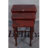 A 20th century nest of three red lacquer occasional tables, the largest 57cm wide x 66cm high.