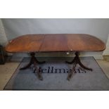 A Regency style inlaid mahogany extending dining table, one extra leaf,