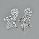 A pair of diamond set earrings of stylized scrolling leaf design,