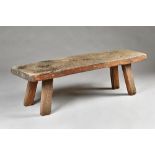 A 19th century pig bench, the rectangular elm slab top on four stake supports,