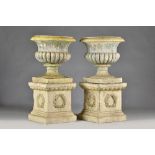 A pair of stoneware garden urns with semi-fluted bodies and turned socles on wreath moulded square